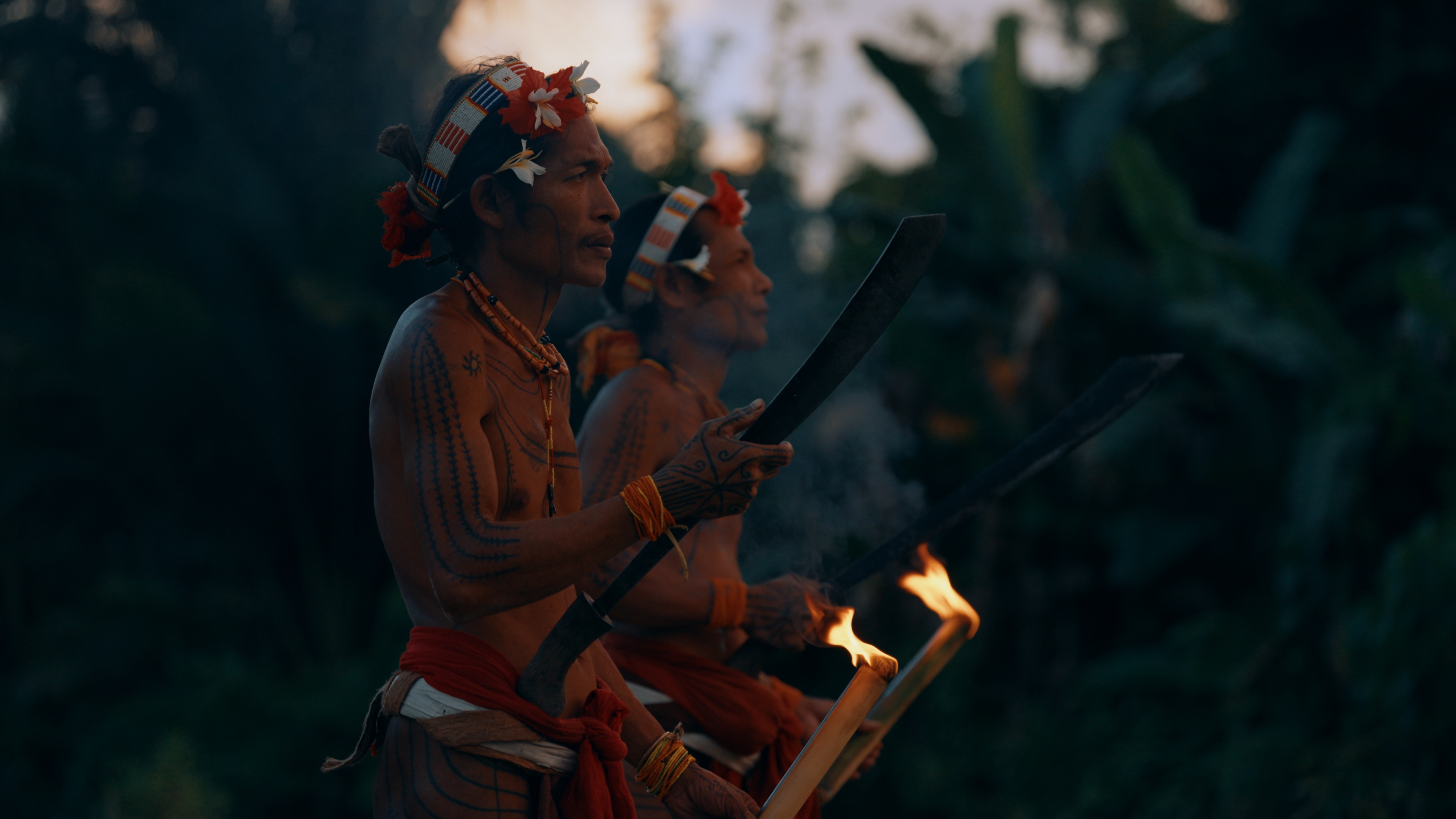 Mentawai men in traditional dress with torches at dusk